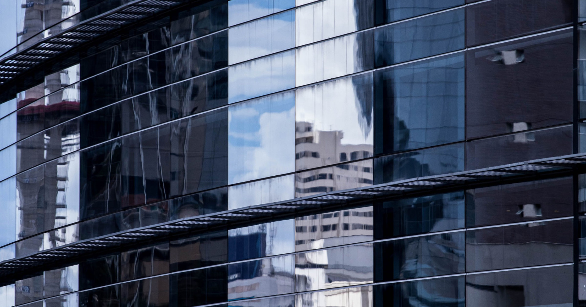 Reflections of surrounding buildings in a glass office tower facade